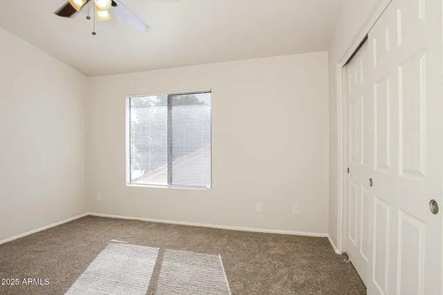 an empty room with a fan & a window