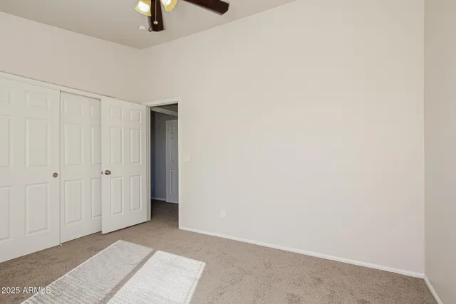 a view of an empty room with window and chandelier fan