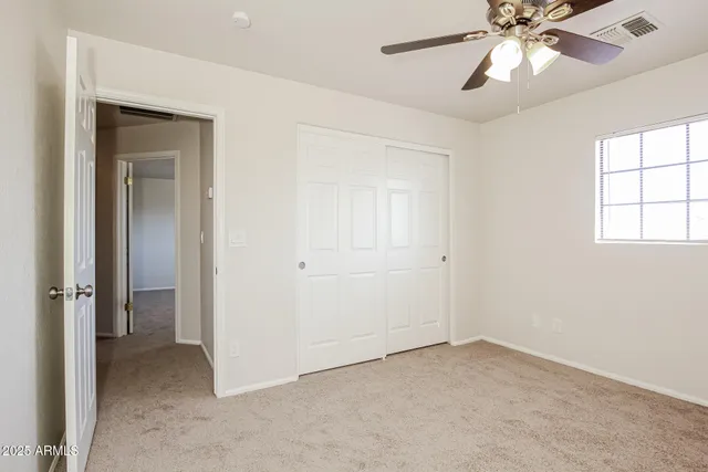 an empty room with a window and a fan