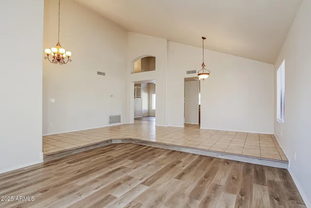 a view of empty room with wooden floor and chandelier