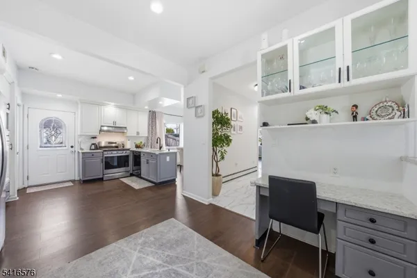 a living room with furniture and a kitchen view with wooden floor