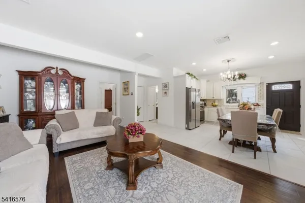 a living room with furniture and a dining table with wooden floor
