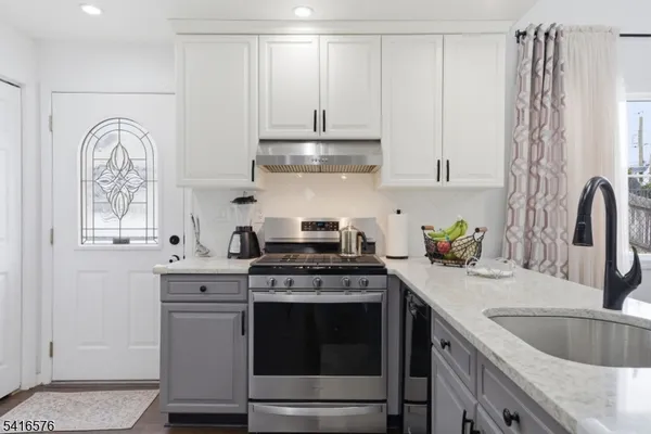 a kitchen with stainless steel appliances granite countertop a sink stove and white cabinets