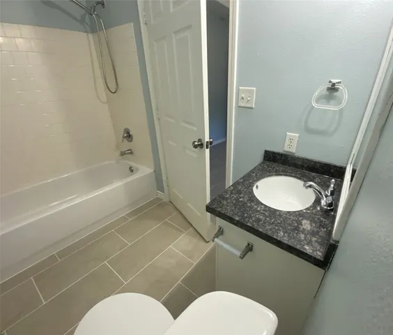 a bathroom with a granite countertop toilet sink and mirror
