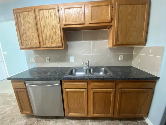 a kitchen with granite countertop wood cabinets stainless steel appliances and sink