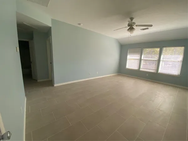 en empty room with windows and chandelier fan