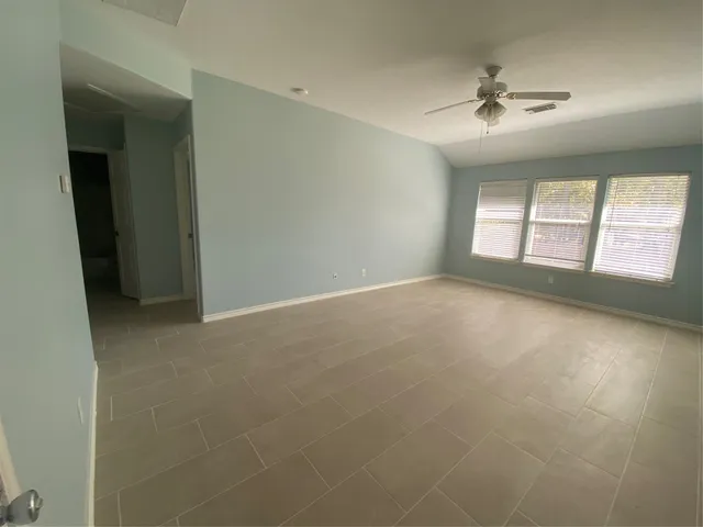 en empty room with windows and chandelier fan