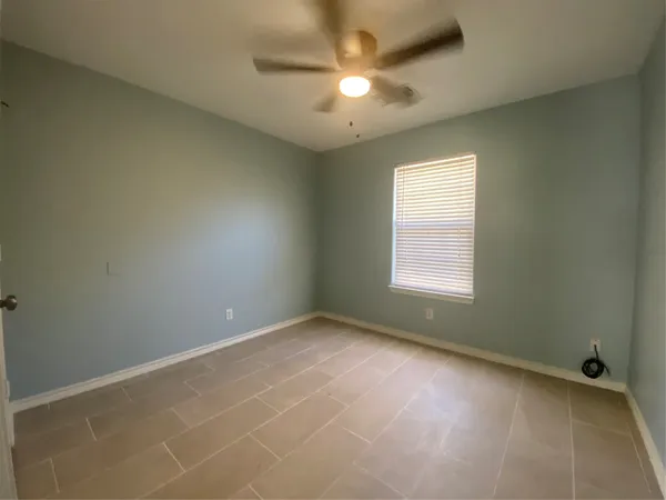 an empty room with a window and a fan