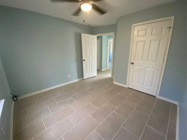 an empty room with a ceiling fan and window