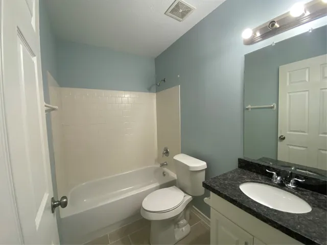 a bathroom with a granite countertop toilet a sink and a mirror