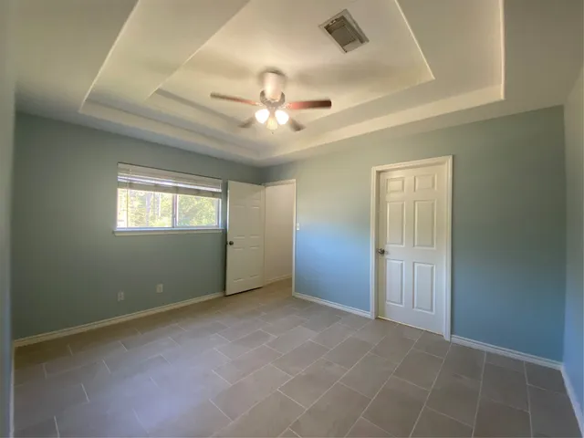 an empty room with windows and fan