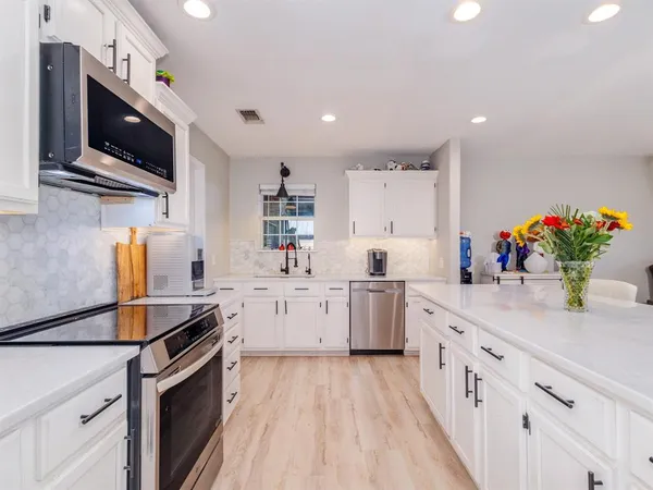 a kitchen that has a lot of cabinets and stainless steel appliances
