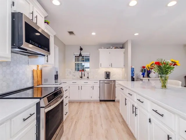 a kitchen that has a lot of cabinets and stainless steel appliances