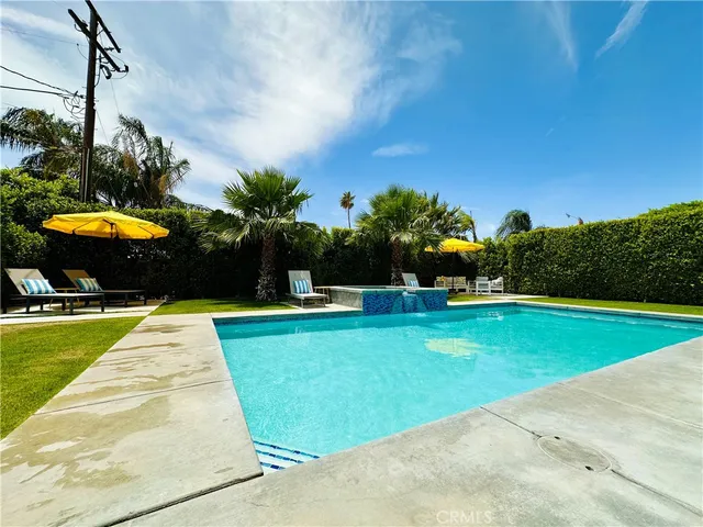 a view of a swimming pool with a yard and palm trees
