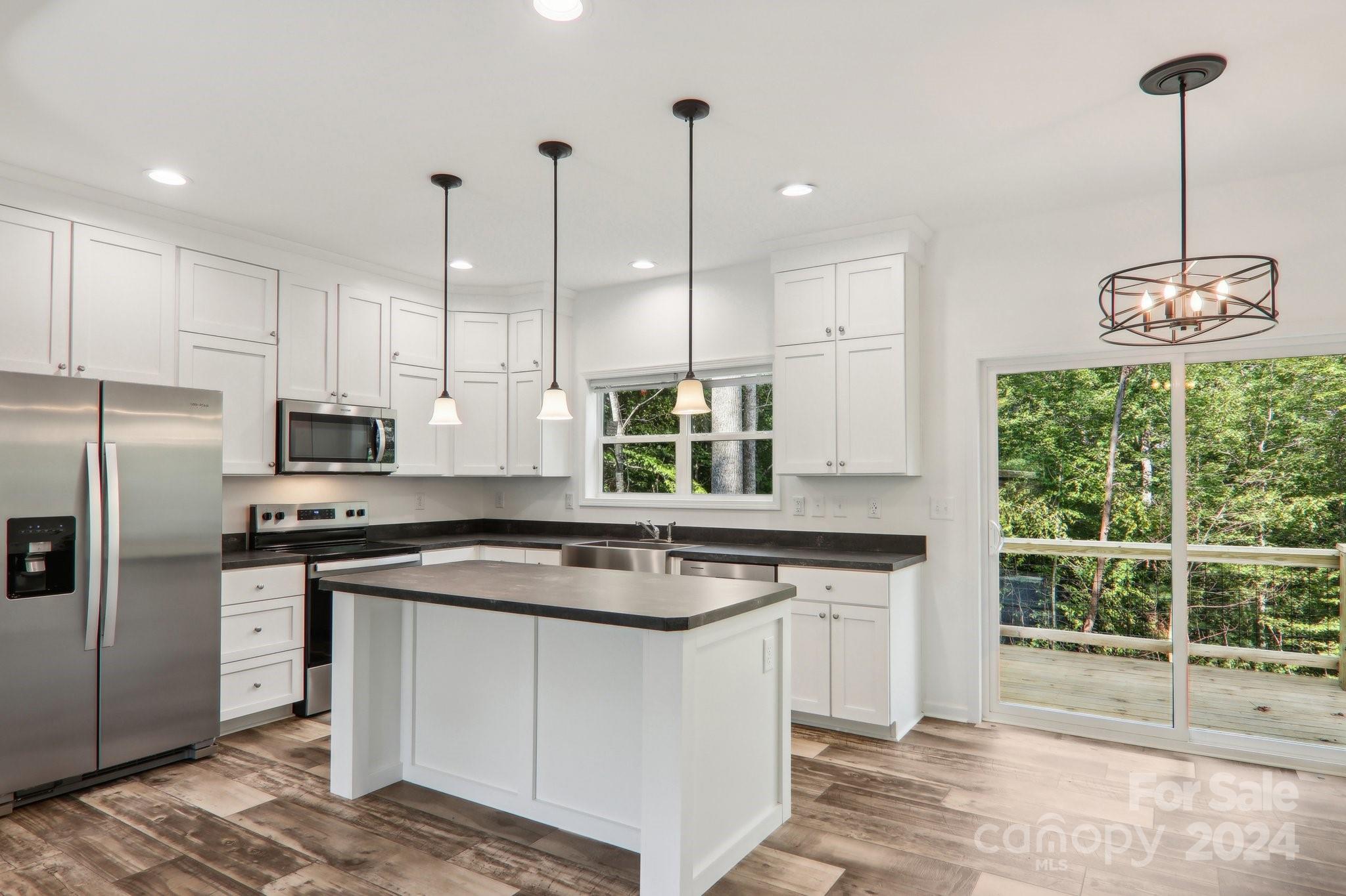 1730 Windswept Ridge Road Marshall, NC 28753 - Photo 12 of 45 a kitchen with stainless steel appliances granite countertop a stove a sink a refrigerator a center island and a wooden floor