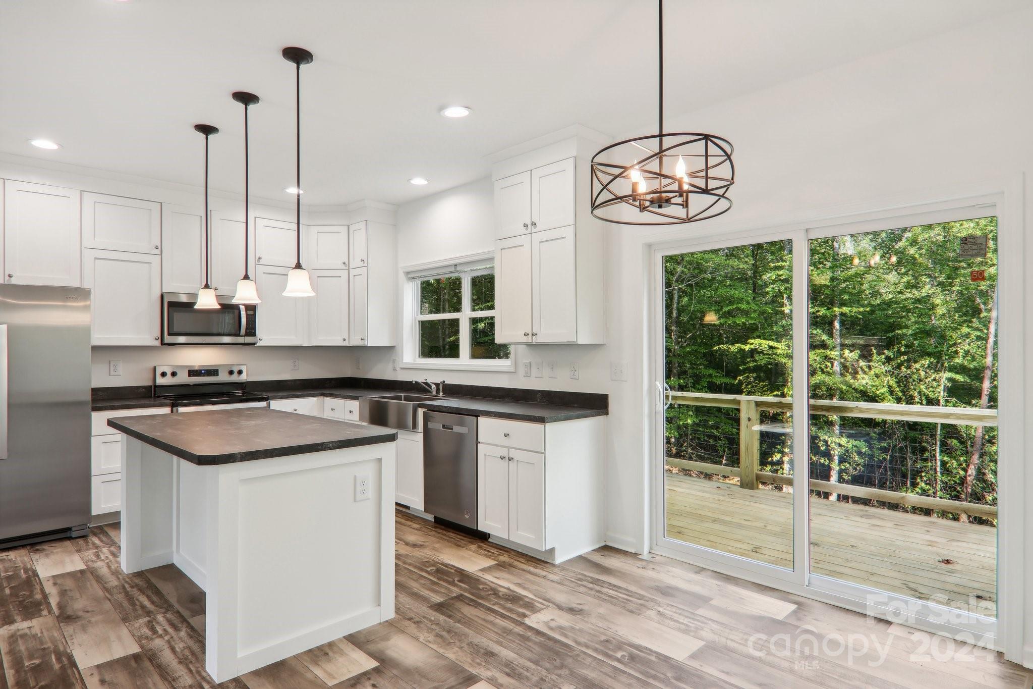 1730 Windswept Ridge Road Marshall, NC 28753 - Photo 15 of 45 a kitchen with stainless steel appliances granite countertop a stove a sink dishwasher and white cabinets with wooden floor