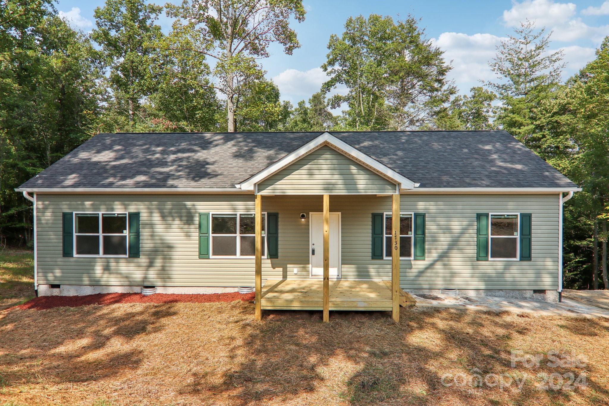 1730 Windswept Ridge Road Marshall, NC 28753 - Photo 4 of 45 a view of a white house with large windows and a small yard