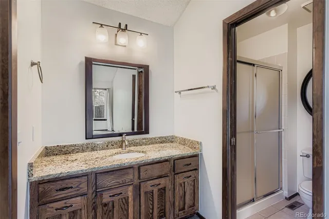 a bathroom with a granite countertop toilet a sink and a mirror