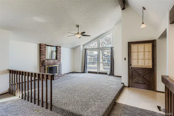 a living room with furniture a flat screen tv and a refrigerator