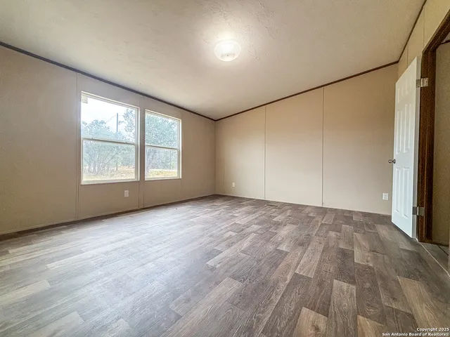 a view of an empty room with a window and wooden floor