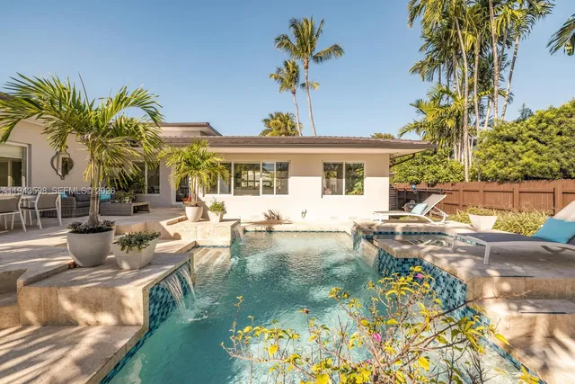 a view of swimming pool with chairs and palm tree