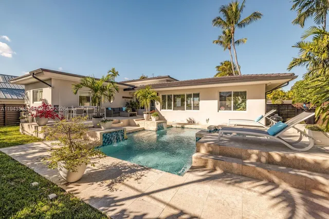an aerial view of a house with swimming pool and large trees