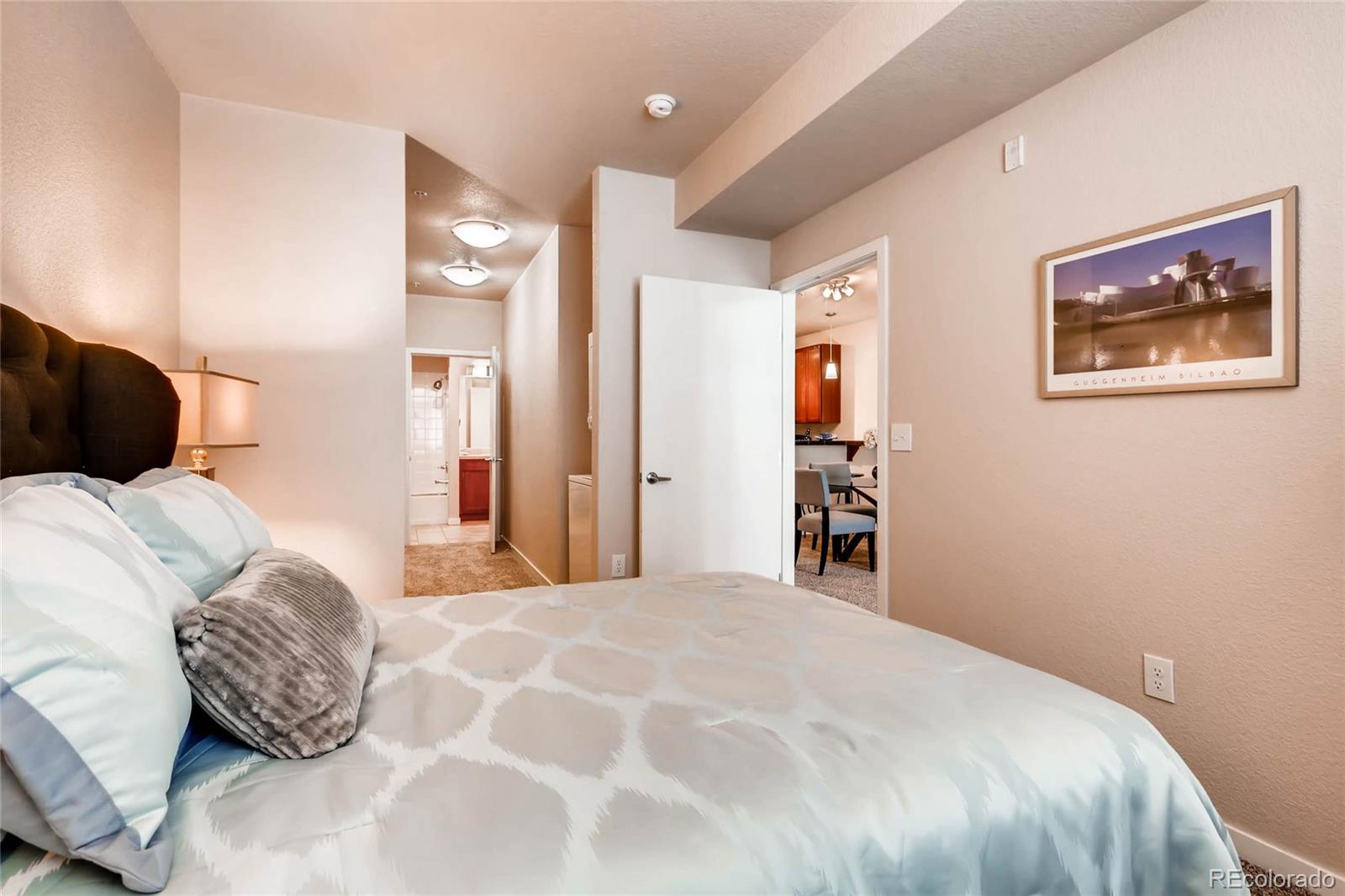 3101 Blake Street, Unit 214 Denver, CO 80205 - Photo 11 of 17 a bedroom with a large bed and a lamp