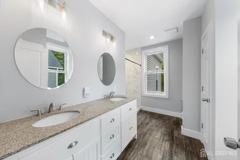a bathroom with a granite countertop double vanity sink and a mirror