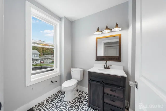 a bathroom with a toilet sink vanity and mirror