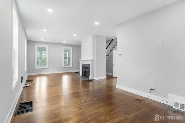 a view of empty room with wooden floor and windows