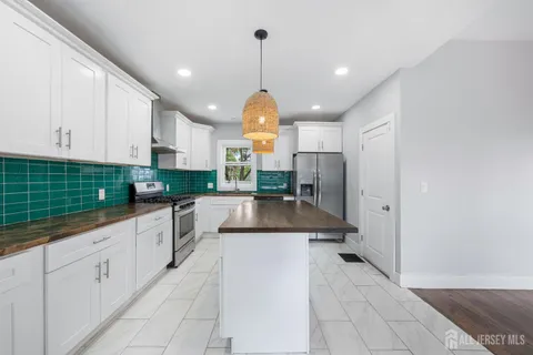 a large kitchen with granite countertop a stove a sink and a refrigerator