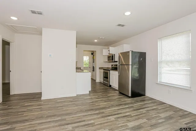 a view of a kitchen with refrigerator and wooden floor