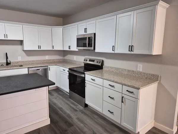a kitchen with wooden floors and white cabinets