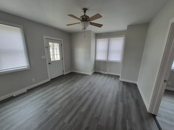 an empty room with wooden floor fan and window
