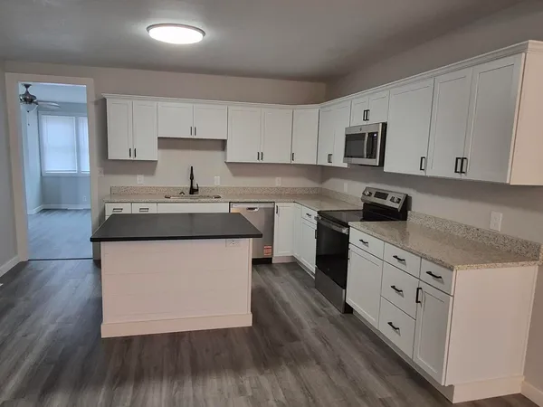 a kitchen with granite countertop white cabinets and white appliances