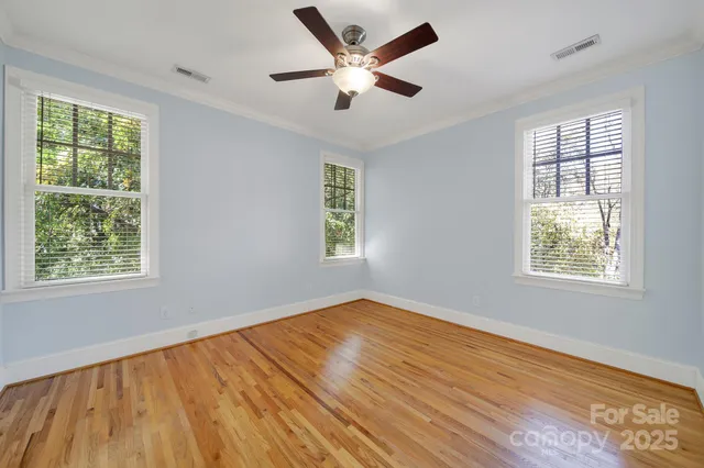 an empty room with wooden floor and a ceiling fan
