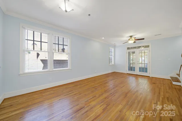 an empty room with wooden floor and windows