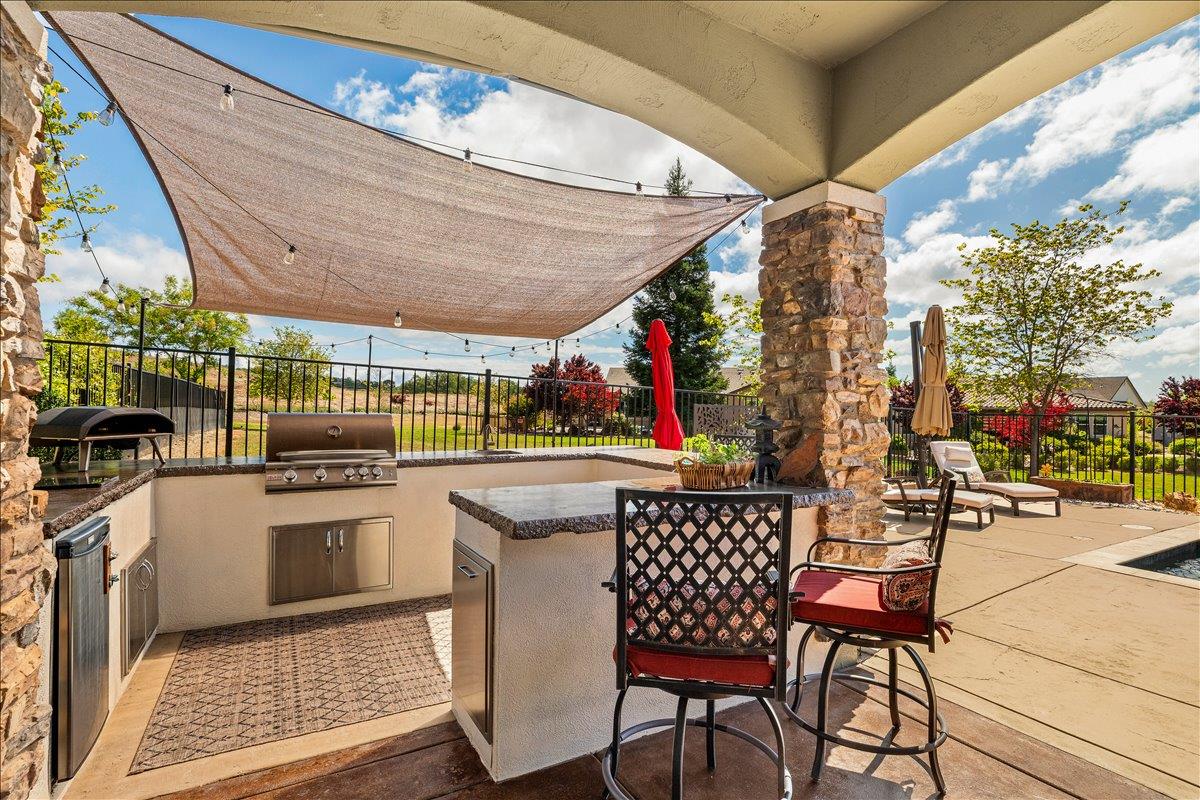 112 Glen View Court Copperopolis, CA 95228 - Photo 53 of 95 Outdoor kitchen has propane BBQ, propane pizza oven, refrigerator and ample seating