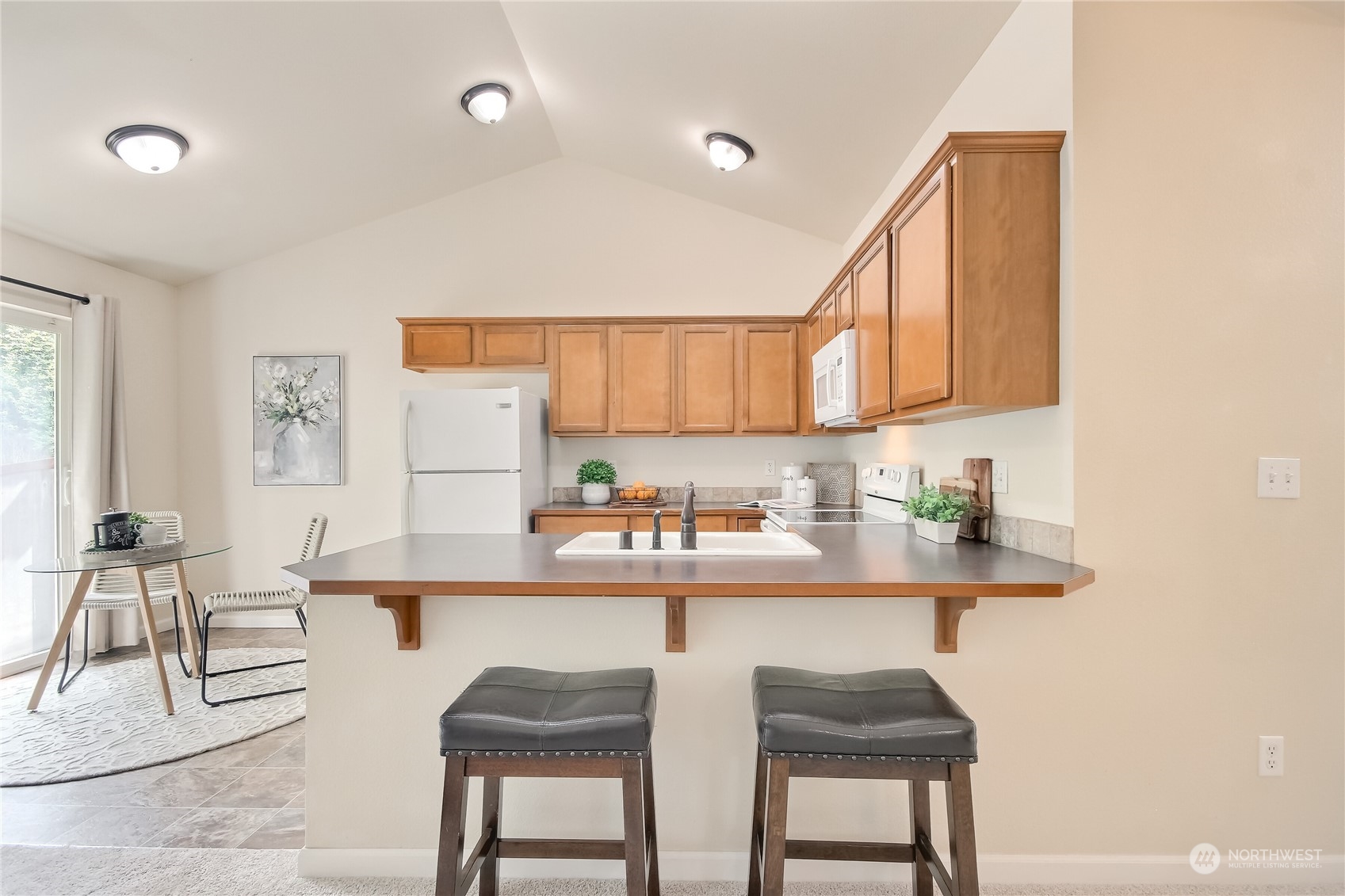 9814 201st Street East Graham, WA 98338 - Photo 7 of 40 a kitchen with stainless steel appliances granite countertop a table and chairs in it