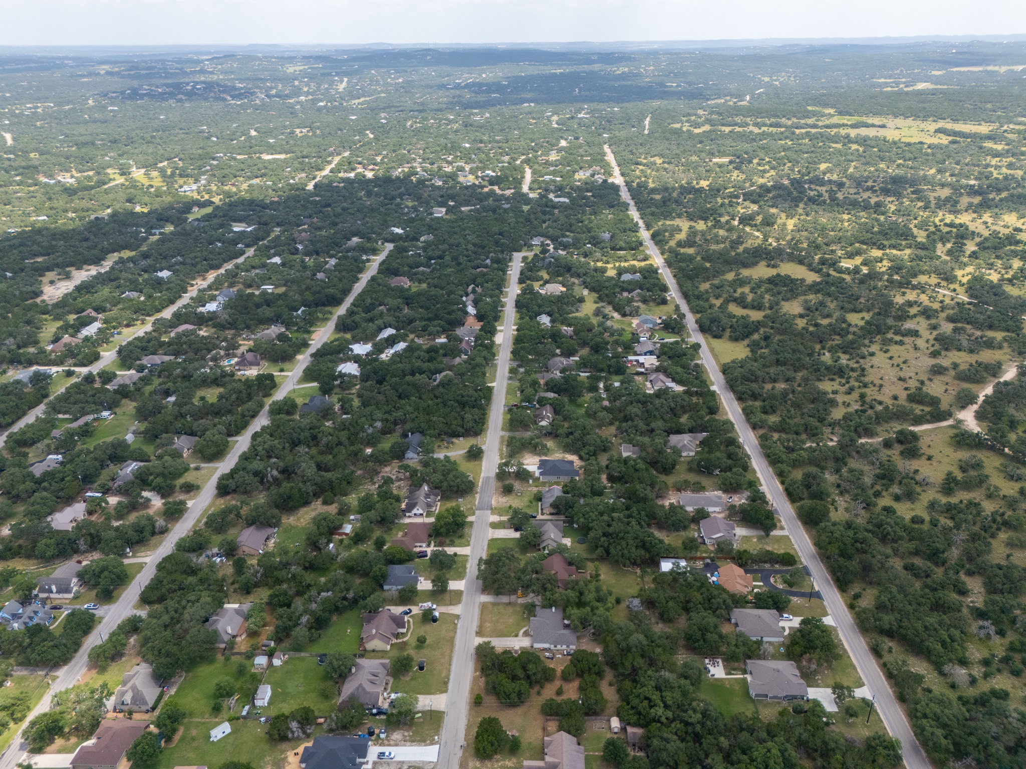 1170 Misty Lane Spring Branch, TX 78070 - Photo 3 of 24 An aerial perspective reveals a vast, tree-lined neighborhood bordering untouched natural landscapes.