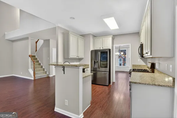 a kitchen with refrigerator and wooden floor