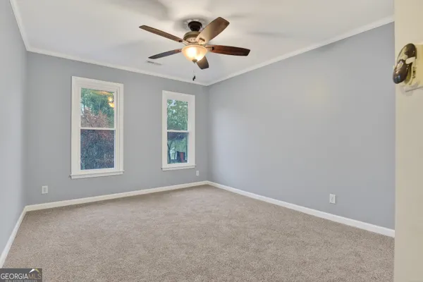 an empty room with windows and fan