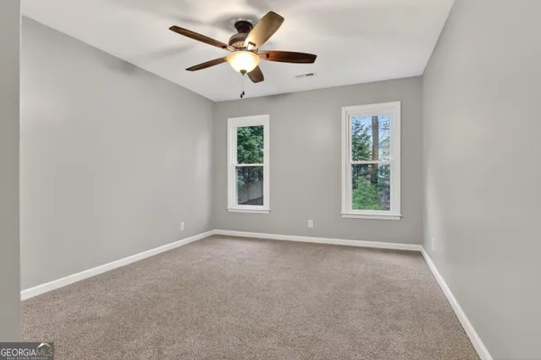 an empty room with windows and fan