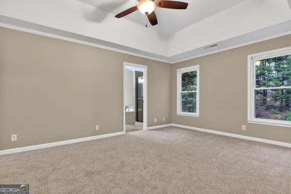 a view of an empty room with window and chandelier fan