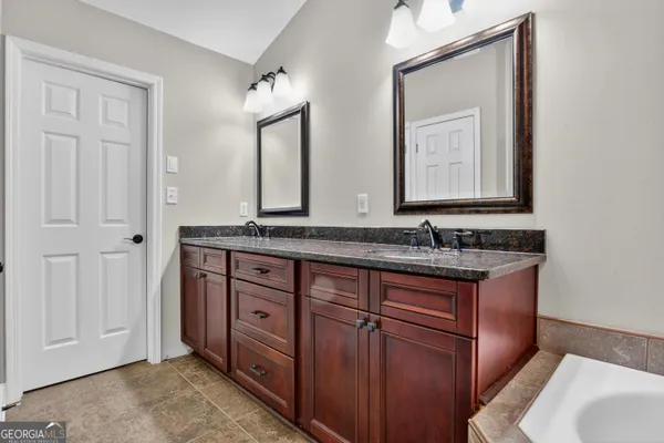 a bathroom with a granite countertop double vanity sink and mirror