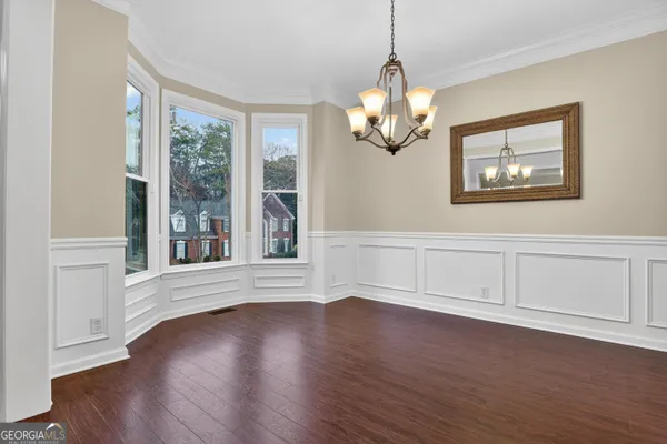 a view of an empty room with wooden floor and fan