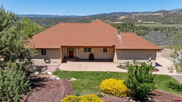 a front view of a house with a garden and mountain view