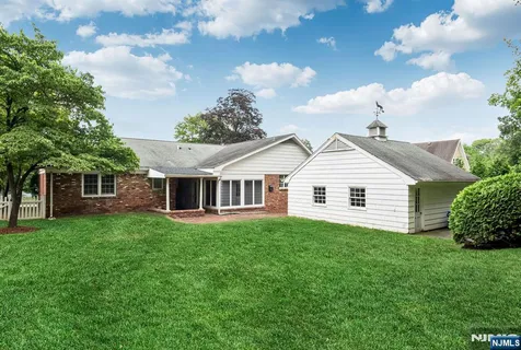 a view of a house with a big yard potted plants and large tree