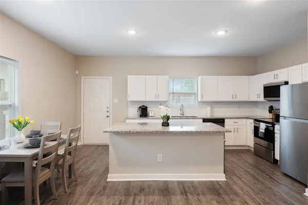 a kitchen with stainless steel appliances granite countertop a table chairs sink and cabinets