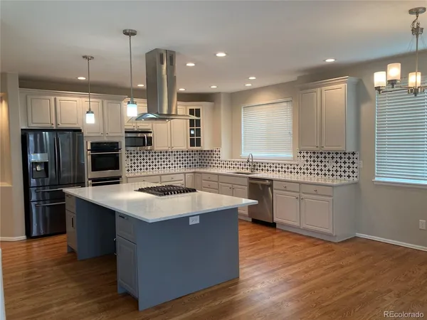 a kitchen with stainless steel appliances kitchen island granite countertop a sink stove and refrigerator